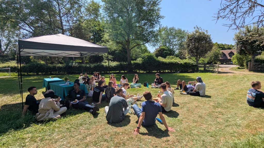 Varnfest Future Leaders attendees sat on the grass in the sunshine at lunchtime. 