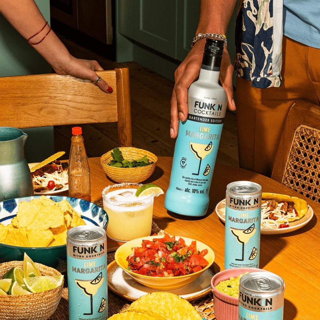 Photograph of a party scene featuring FUNKIN cocktail cans and bottles alongside nachos.