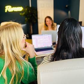 Over the shoulder of 2 women working on a single laptop