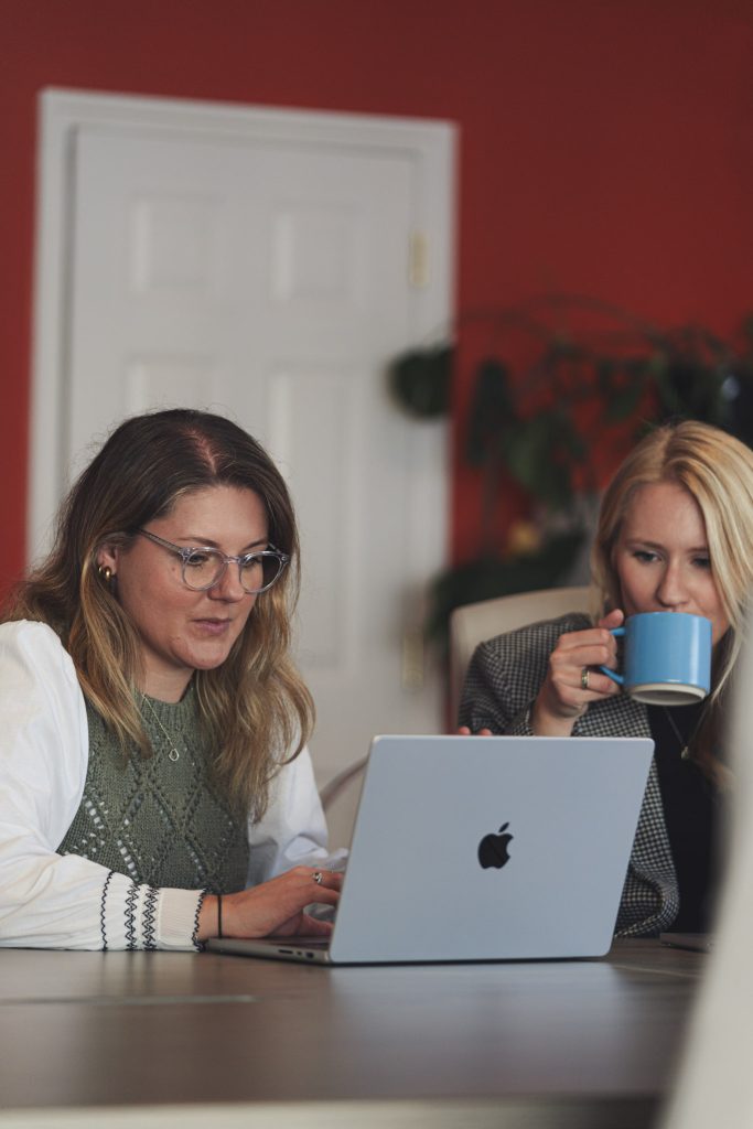 2 women working of a single laptop